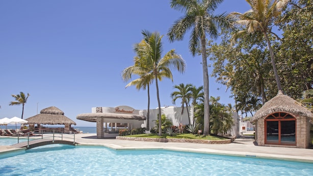 A resort pool area with a bridge, palm trees, and a restaurant. - Gaviana Resort (Mazatlán)