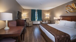 A hotel room with a bed, a desk, a chair, a sofa, and a TV.