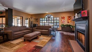 A spacious lobby with a fireplace, sofas, and a large window providing natural light.