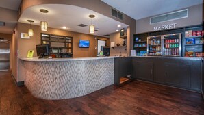 A reception area with a curved counter, a television, and a market section with refrigerated items.