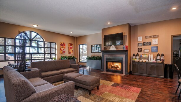 A spacious living room with a large sectional sofa, a fireplace, and a kitchen area with a coffee station.