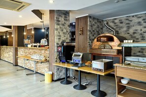 A modern bar area with a stone wall, a coffee machine, and a pizza oven. - Hotel Europacity (Brussels)