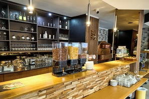 A bar area with coffee dispensers, a wine bottle, and a variety of glasses.