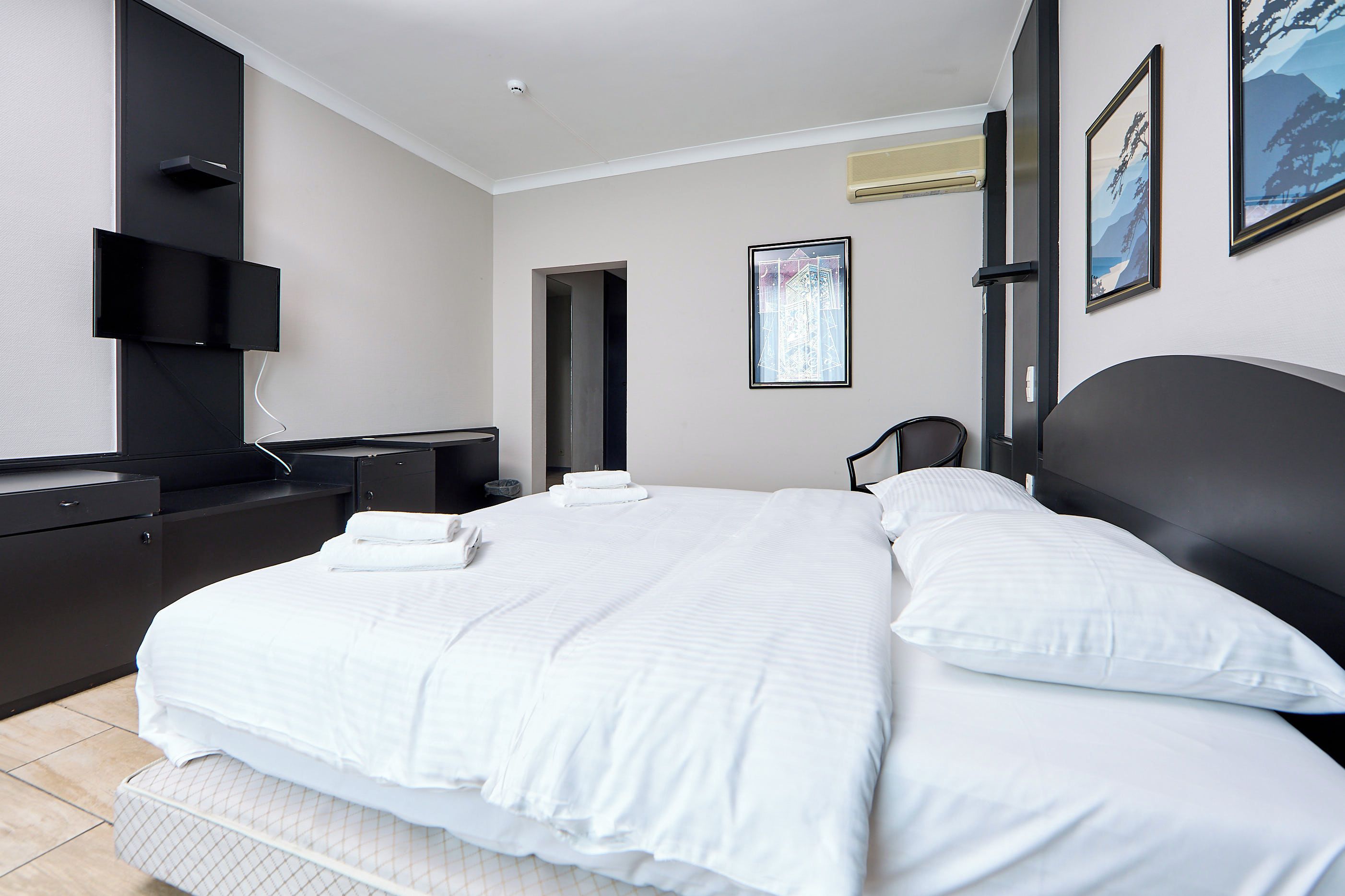 Habitación de hotel moderna con una cama grande, un televisor de pantalla plana montado en la pared y una ventana con vistas al exterior.