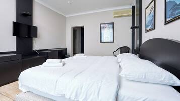 Habitación de hotel moderna con una cama grande, un televisor de pantalla plana montado en la pared y una ventana con vistas al exterior.