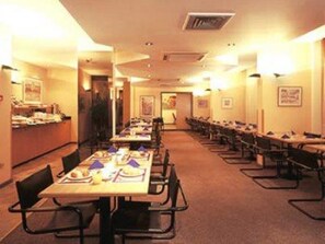 A conference room with long tables and chairs, equipped with nameplates and documents.