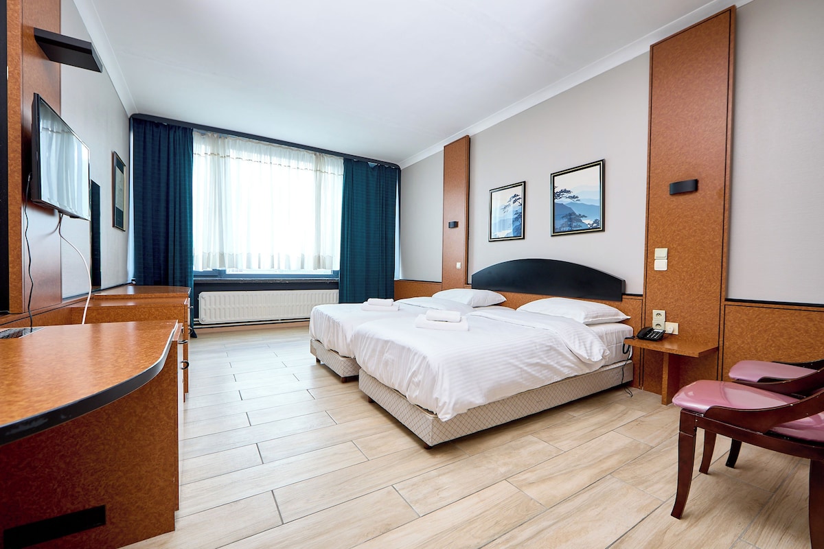 A hotel room with a bed, bedside tables, a desk, and a chair.