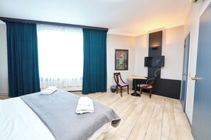 A hotel room with two beds, a desk, a chair, a TV, and a painting on the wall. - Hotel Europacity (Brussels)
