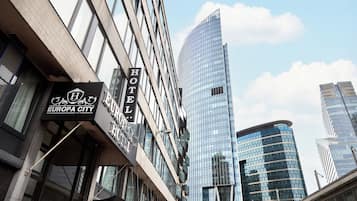Un hôtel avec une enseigne indiquant « EUROPA CITY HOTEL » et un bâtiment moderne en verre en arrière-plan.