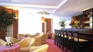 A hotel lobby with round tables, chairs, and a bar area. - Hotel Europacity (Brussels)