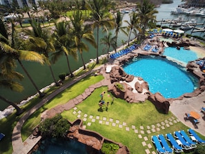 Un resort con una piscina grande, palmeras y un puerto deportivo.