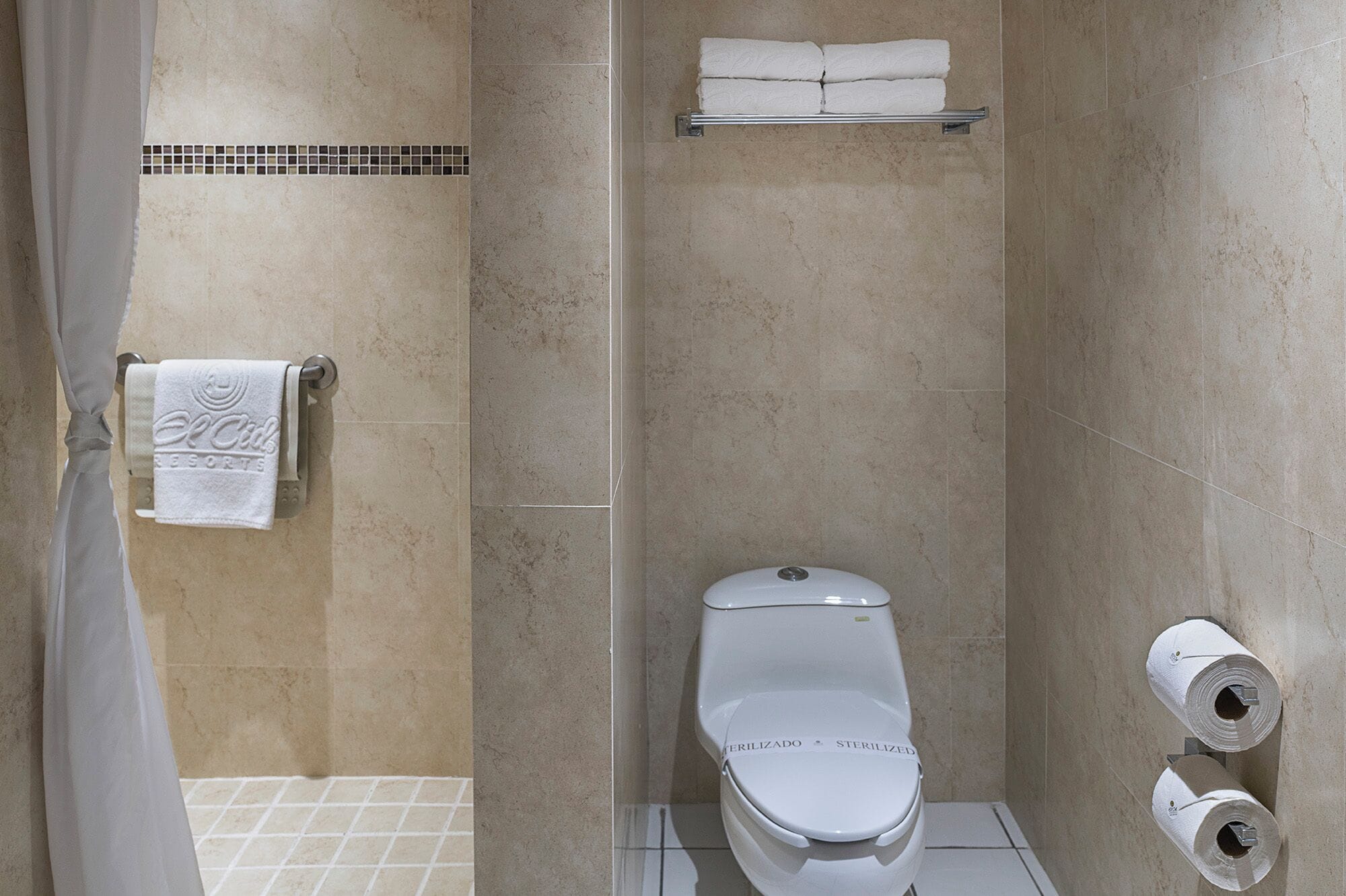 Ein Badezimmer mit Toilette, Handtuchhalter mit Handtuch und Toilettenpapier.