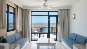 Una habitación con un amplio ventanal corredero que da a un balcón con vista al mar.