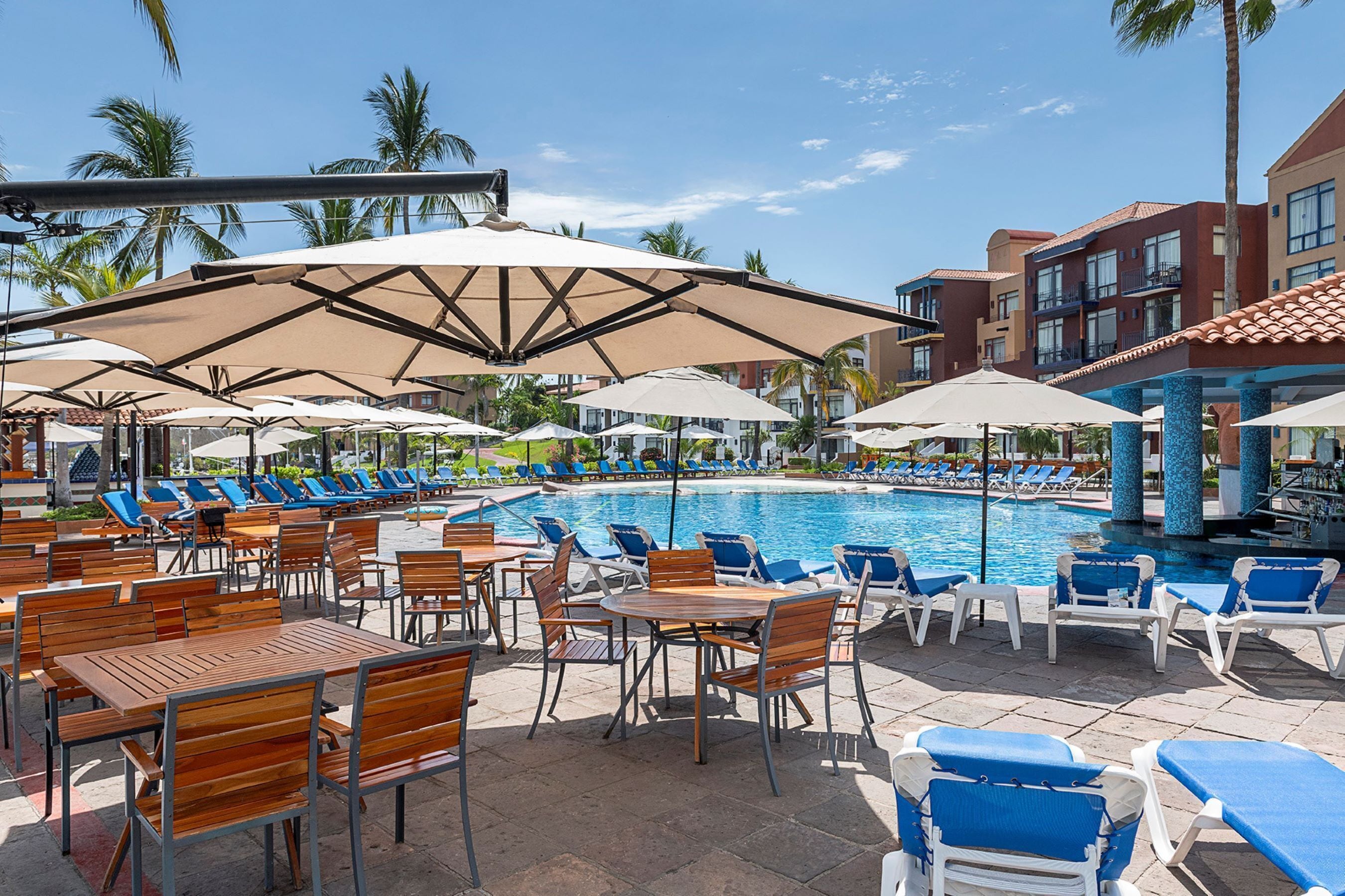 A poolside area with lounge chairs, umbrellas, and wooden tables.