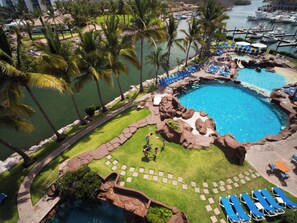 Un resort con una piscina grande, palmeras y un puerto deportivo.