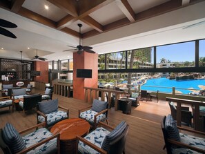 A spacious outdoor lounge area with multiple seating options, a pool view, and a bar area. - El Cid El Moro Beach Hotel (Mazatlán)