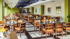 A spacious dining area with multiple tables and chairs, a bar in the background, and artwork on the walls. - El Cid El Moro Beach Hotel (Mazatlán)