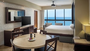 A hotel room with a bed, a desk, a television, a dining table, and a view of the sea. - El Cid El Moro Beach Hotel (Mazatlán)