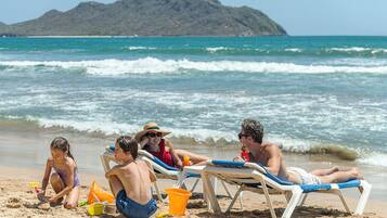 En la playa, sillas reclinables de playa, sombrillas, toallas de playa
