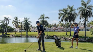 A golf course with a pond, palm trees, and a clubhouse in the background. - El Cid El Moro Beach Hotel (Mazatlán)