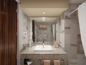 A modern bathroom with a large sink, mirror, and shower.