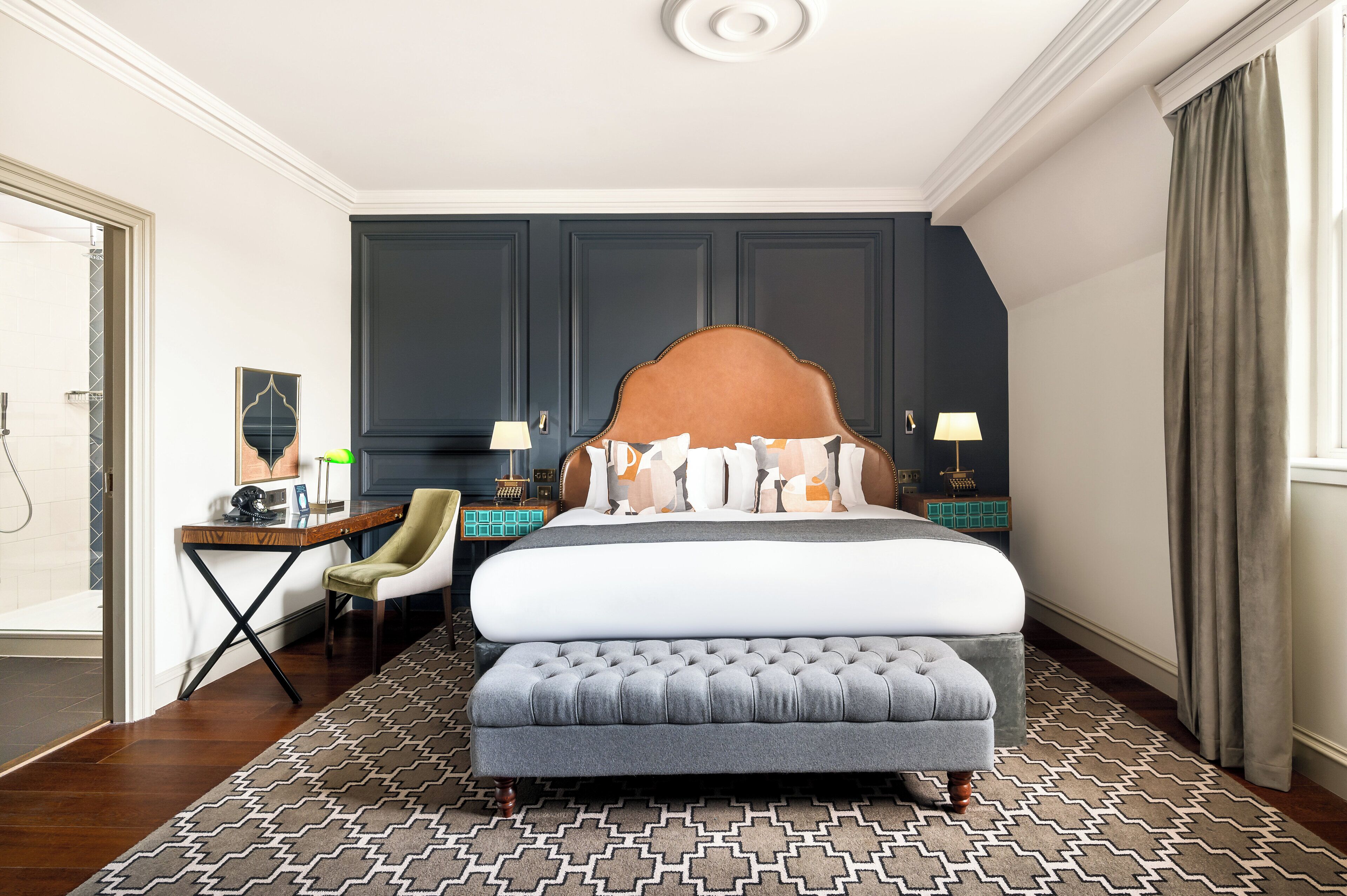 A modern hotel room with a large bed, a desk, and a chair.