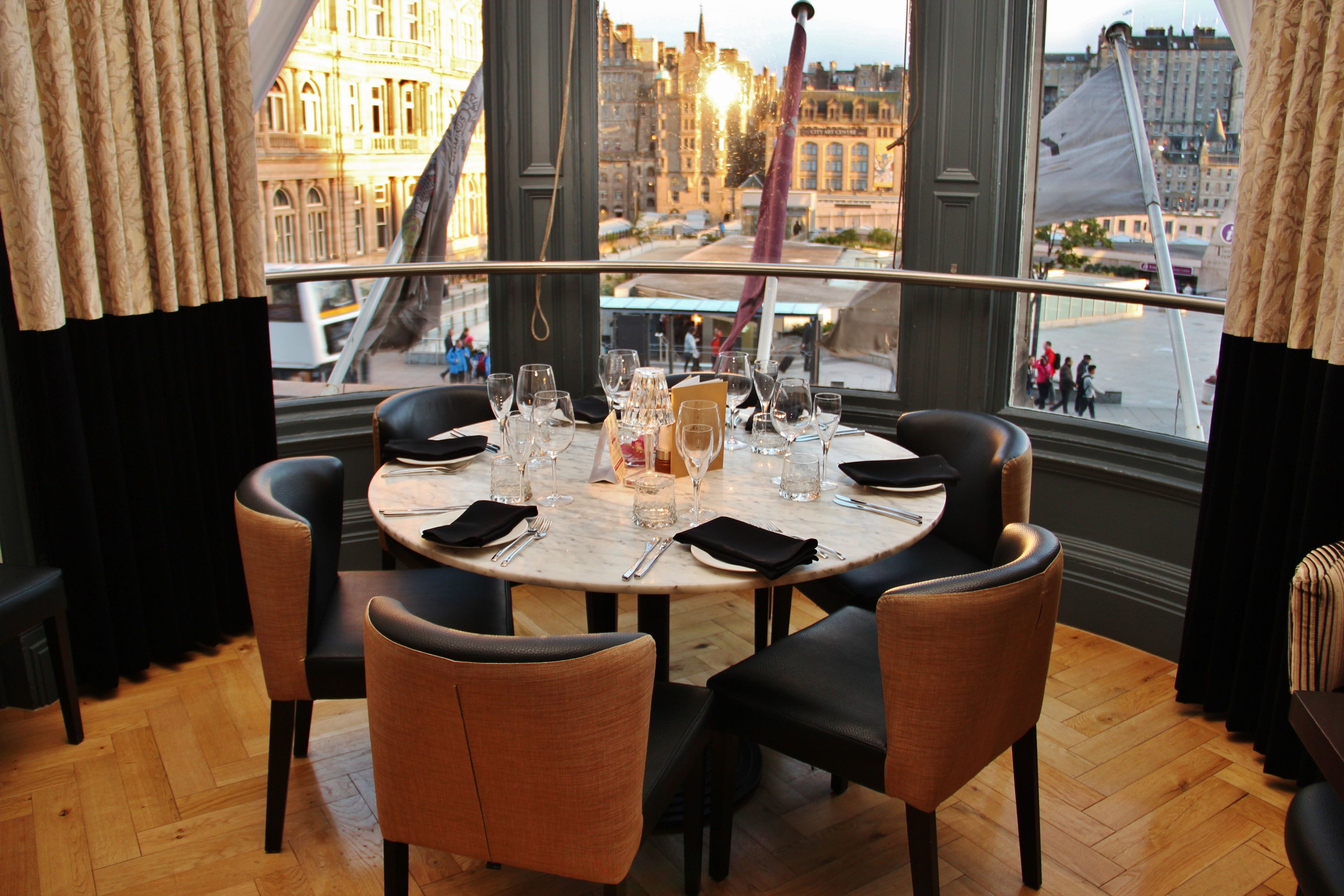 A dining table set for six with a city view through large windows.