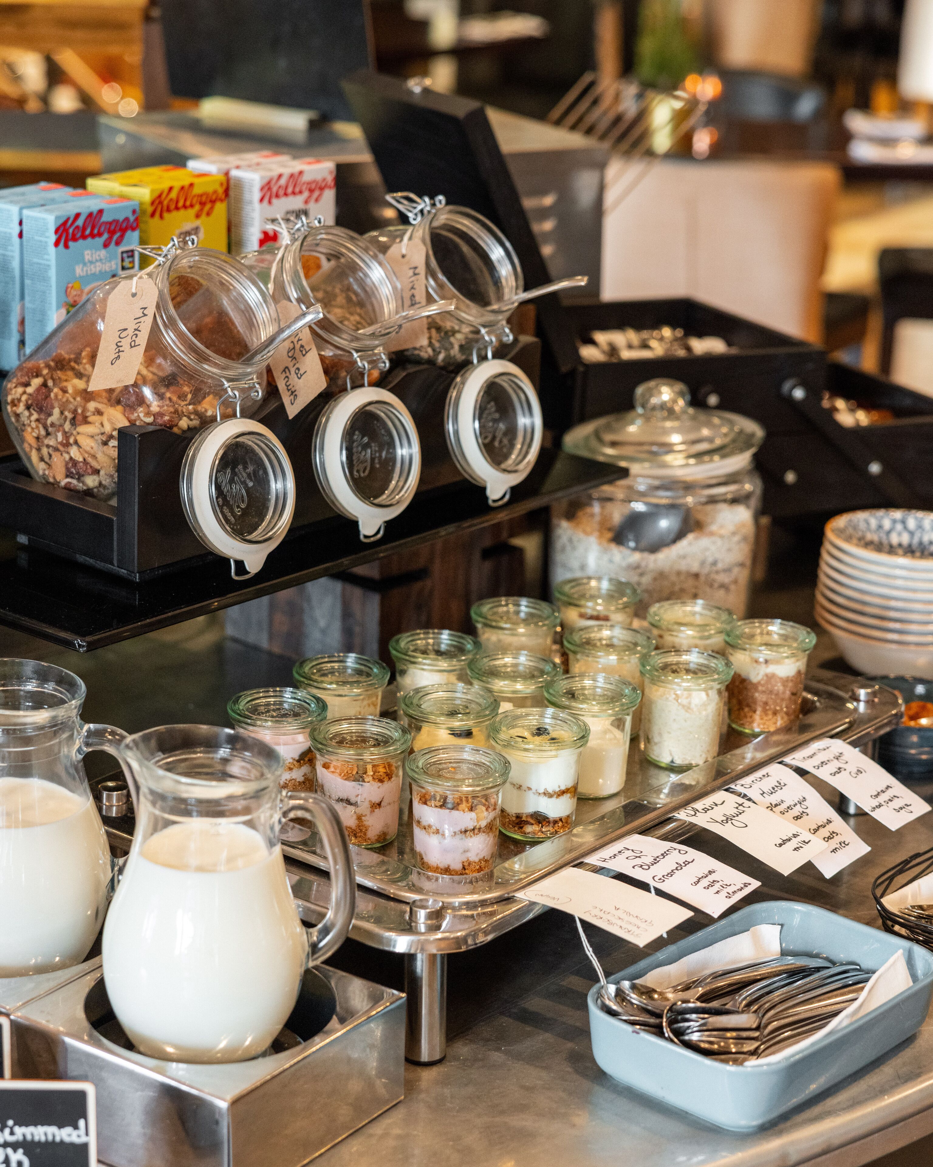 Un buffet con diversi alimenti e contenitori, tra cui vasetti di salse e un vassoio con posate.