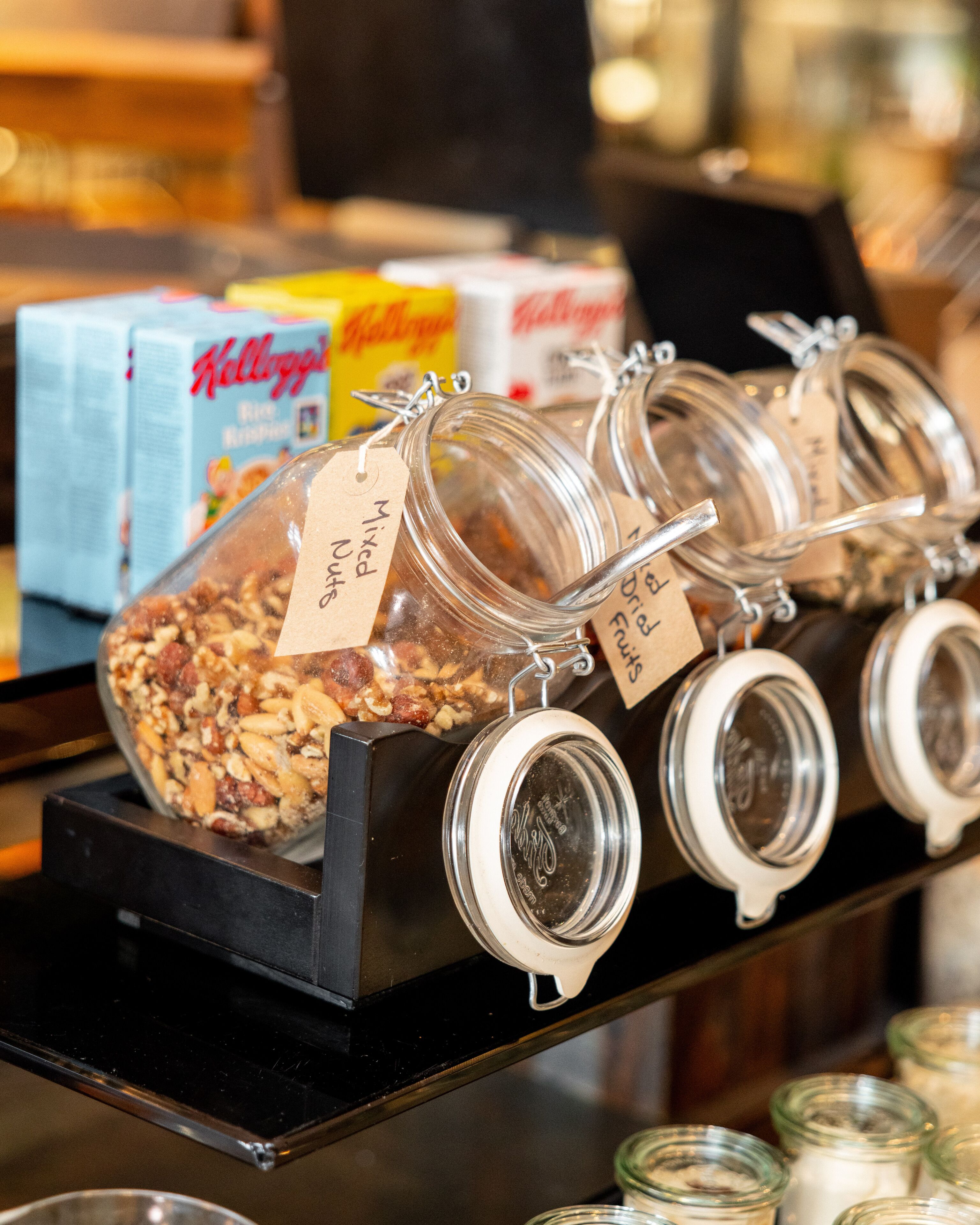 A display of jars with labels, a box of Kellogg's Rice Krispies, and a black stand.