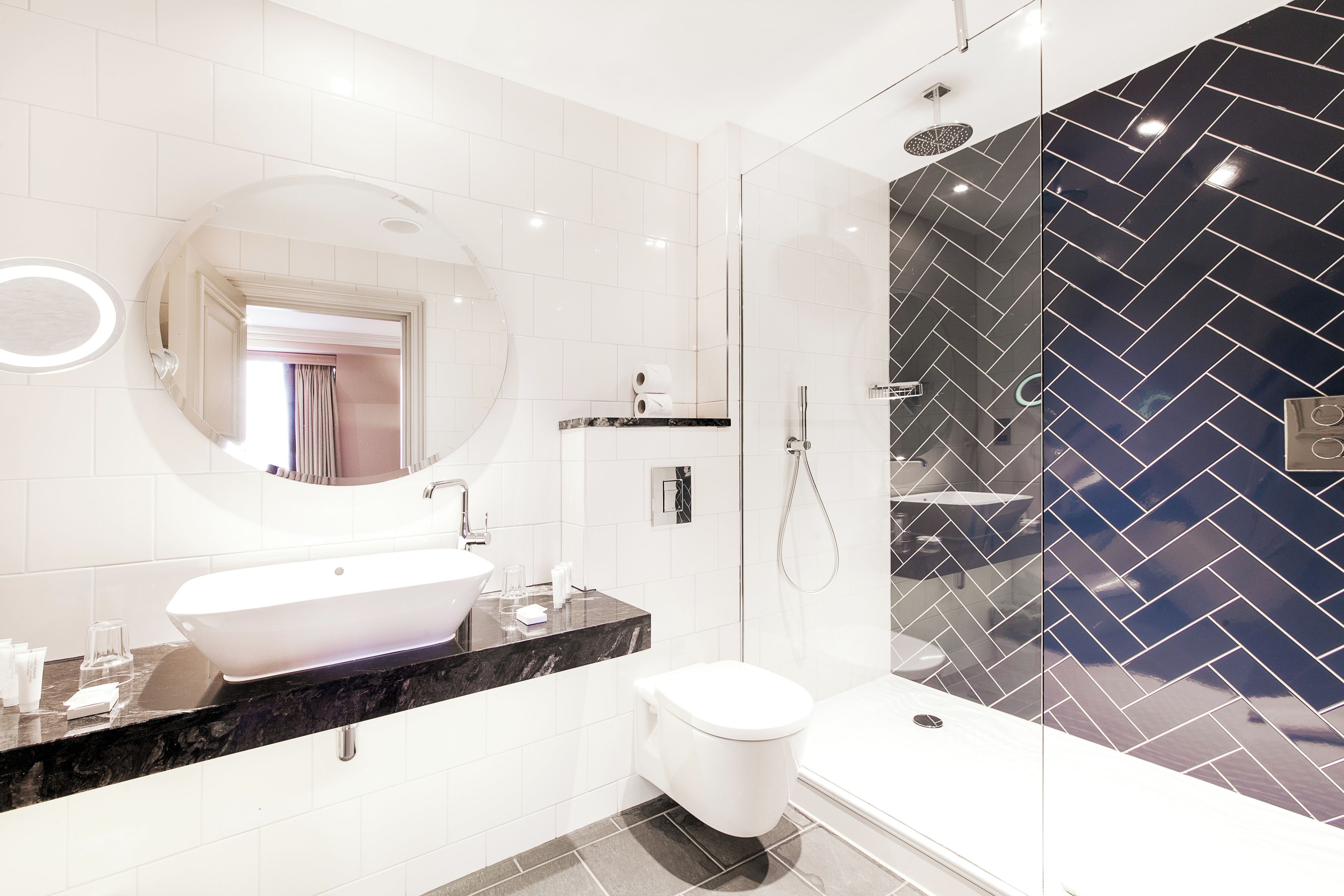 A modern bathroom with a white sink, a toilet, and a glass-enclosed shower area.