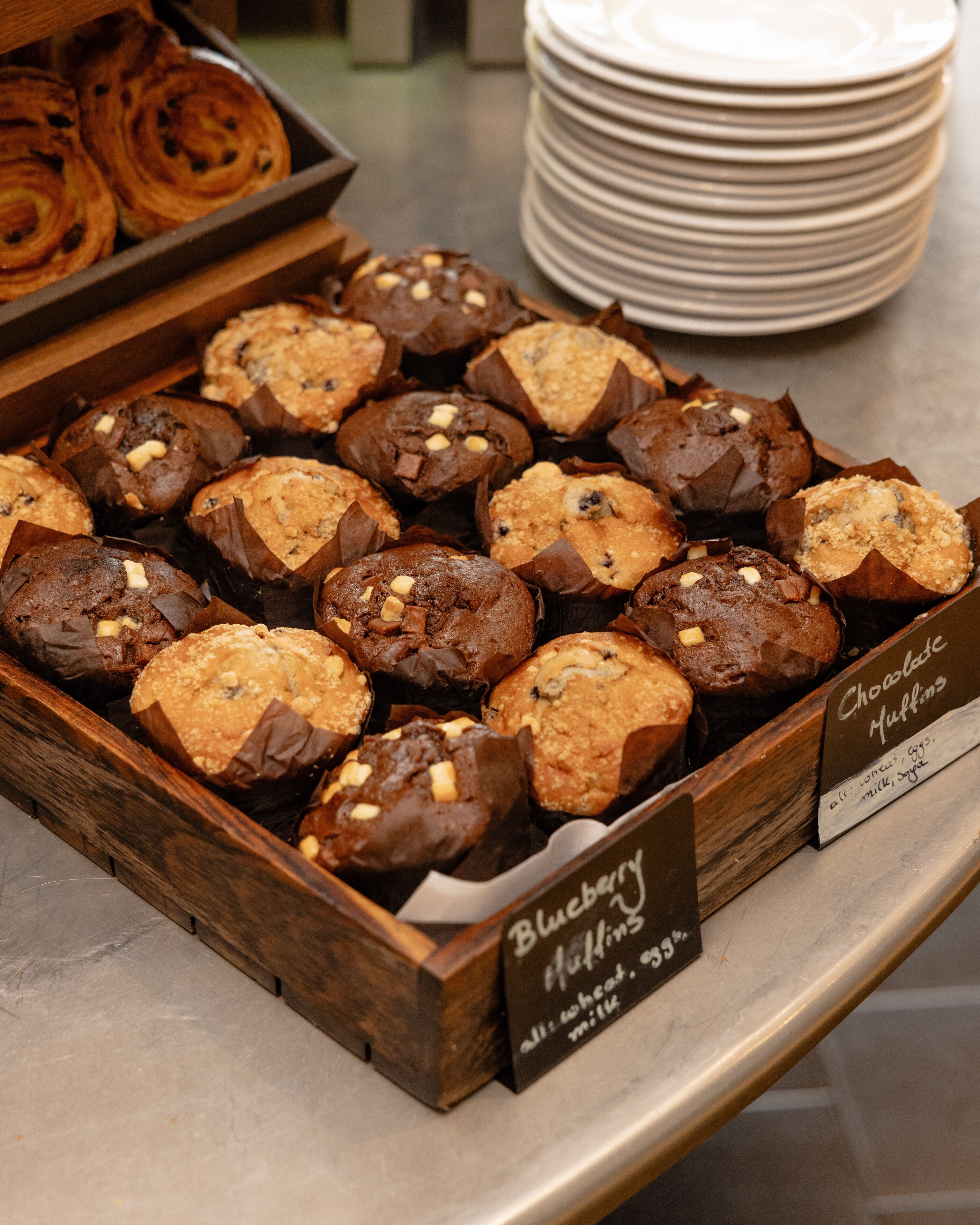 Una bandeja de muffins con etiquetas que indican sabores como arándano y chocolate.