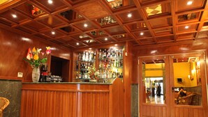 A bar area with wooden paneling, a checkered floor, and a variety of bottles on shelves.