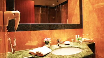 Un baño con lavamanos de mármol, toallero, secador de pelo y espejo.