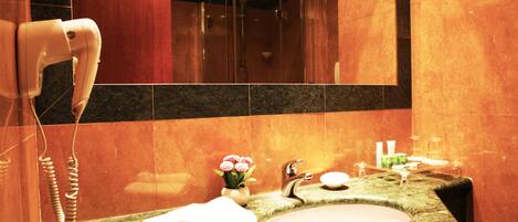 A bathroom with a marble sink, a towel rack, a hairdryer, and a mirror.
