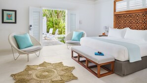 Un dormitorio con una cama, dos sillas, un banco, un tapiz tejido y vistas a un espacio exterior con plantas.