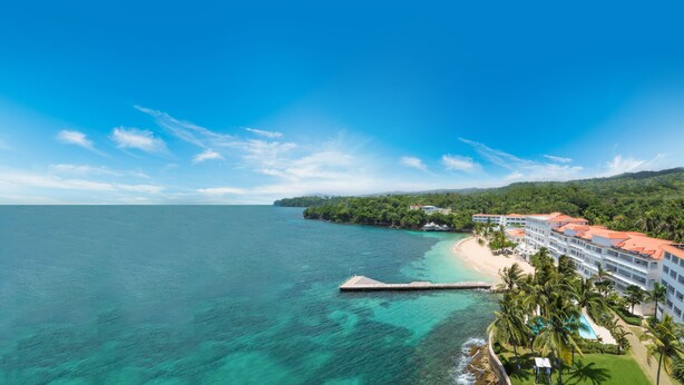 A resort with a beach, ocean, and lush greenery.