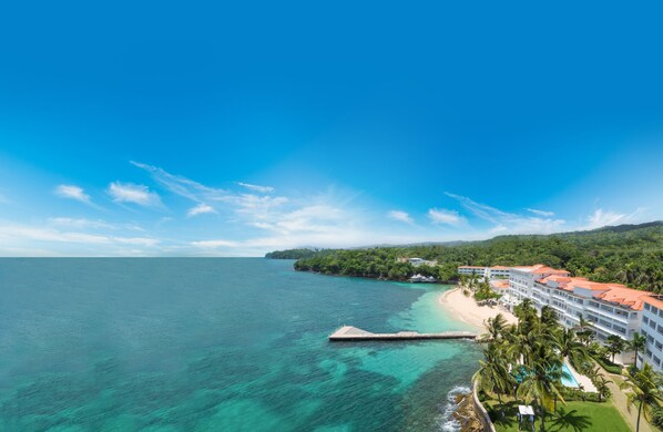 A resort with a beach, ocean, and lush greenery.