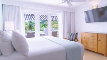 Une chambre d’hôtel avec un lit, un téléviseur fixé au mur, une armoire en bois et un balcon avec des rideaux.