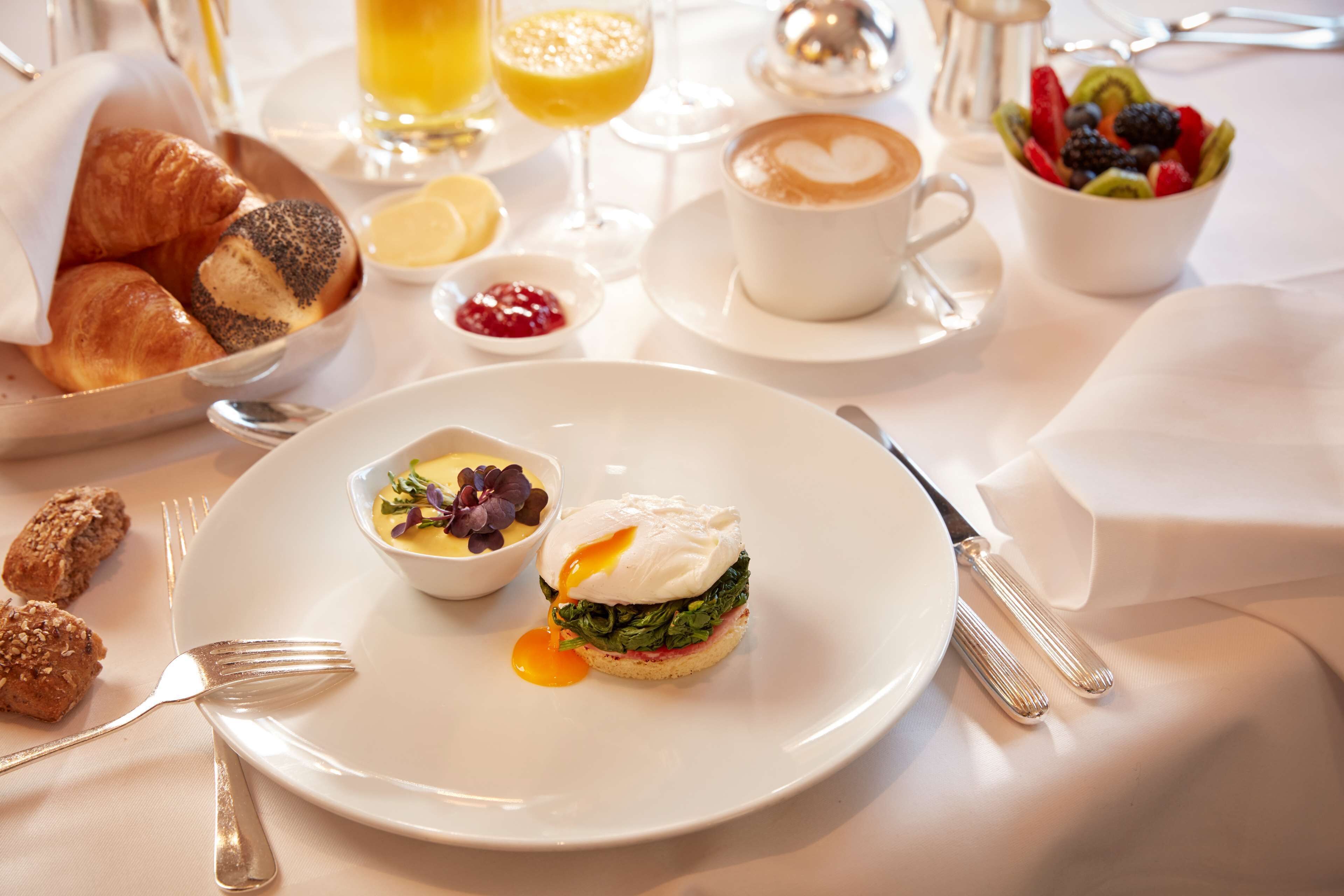 A breakfast setting with croissants, a poached egg, and a cup of coffee.