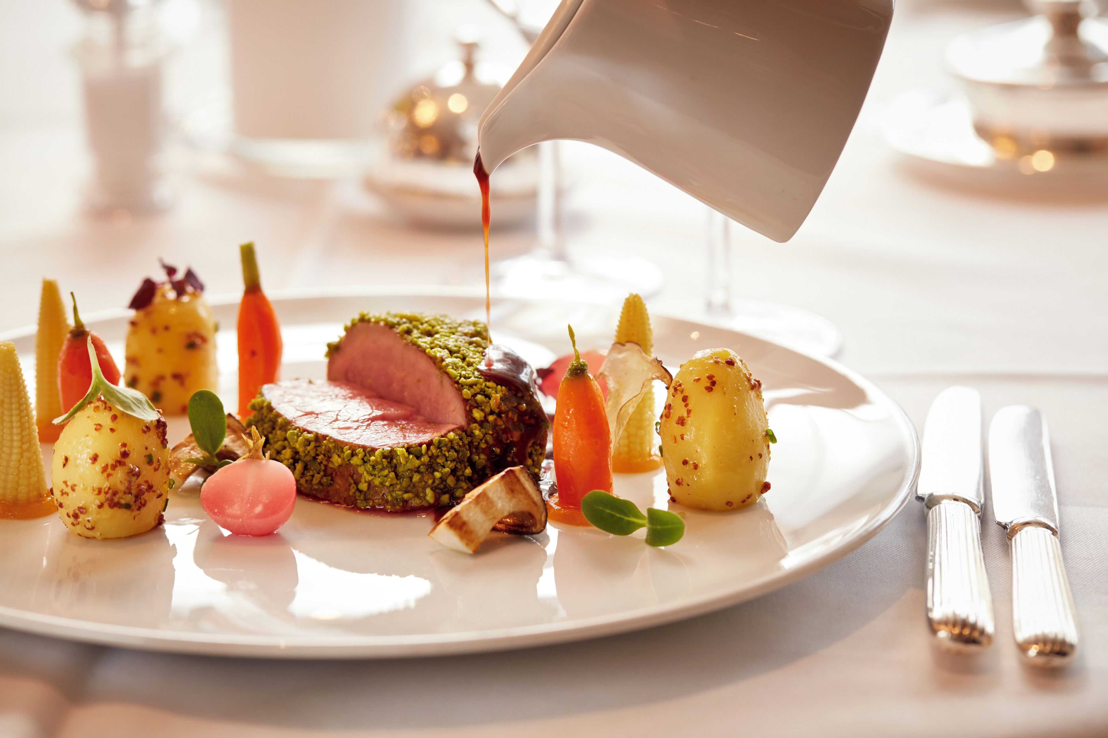 A plated dish with various garnishes and a sauce being poured over it.