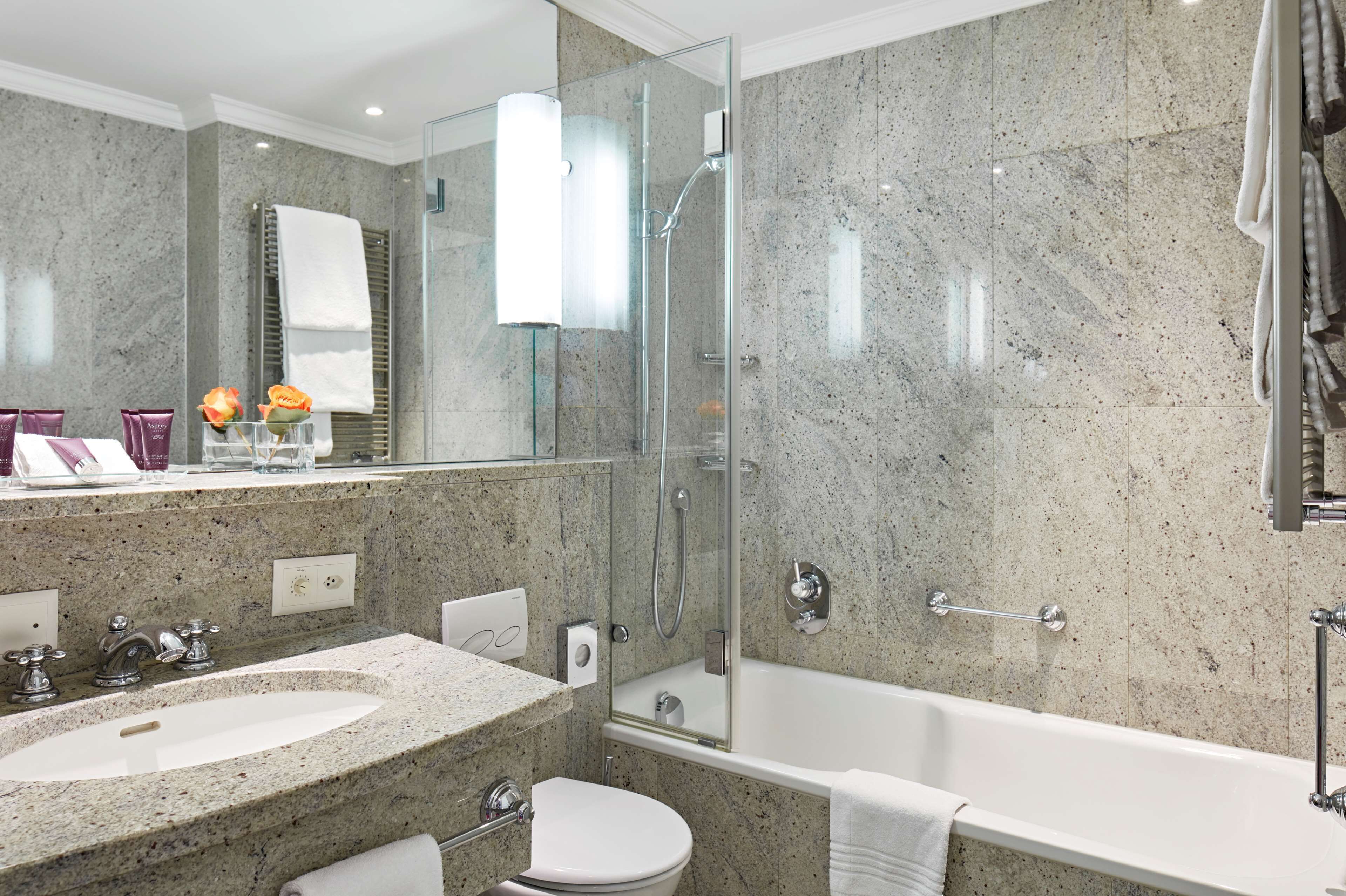Une salle de bain moderne dotée d’une douche à parois de verre, d’une baignoire sur pieds et d’un meuble-lavabo à deux vasques.