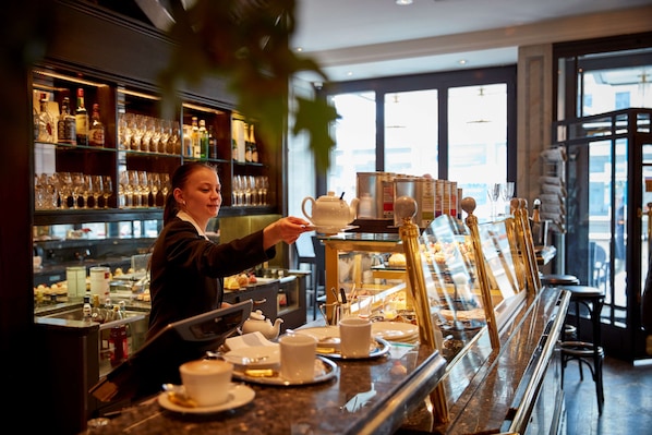 A bar area with a counter, shelves with bottles, and a display case with food items.