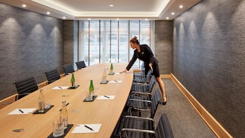 A conference room with a long table, chairs, and a person arranging items.