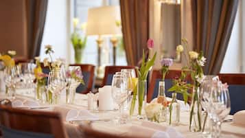 A dining table set for a formal meal with glassware, cutlery, and floral centerpieces.