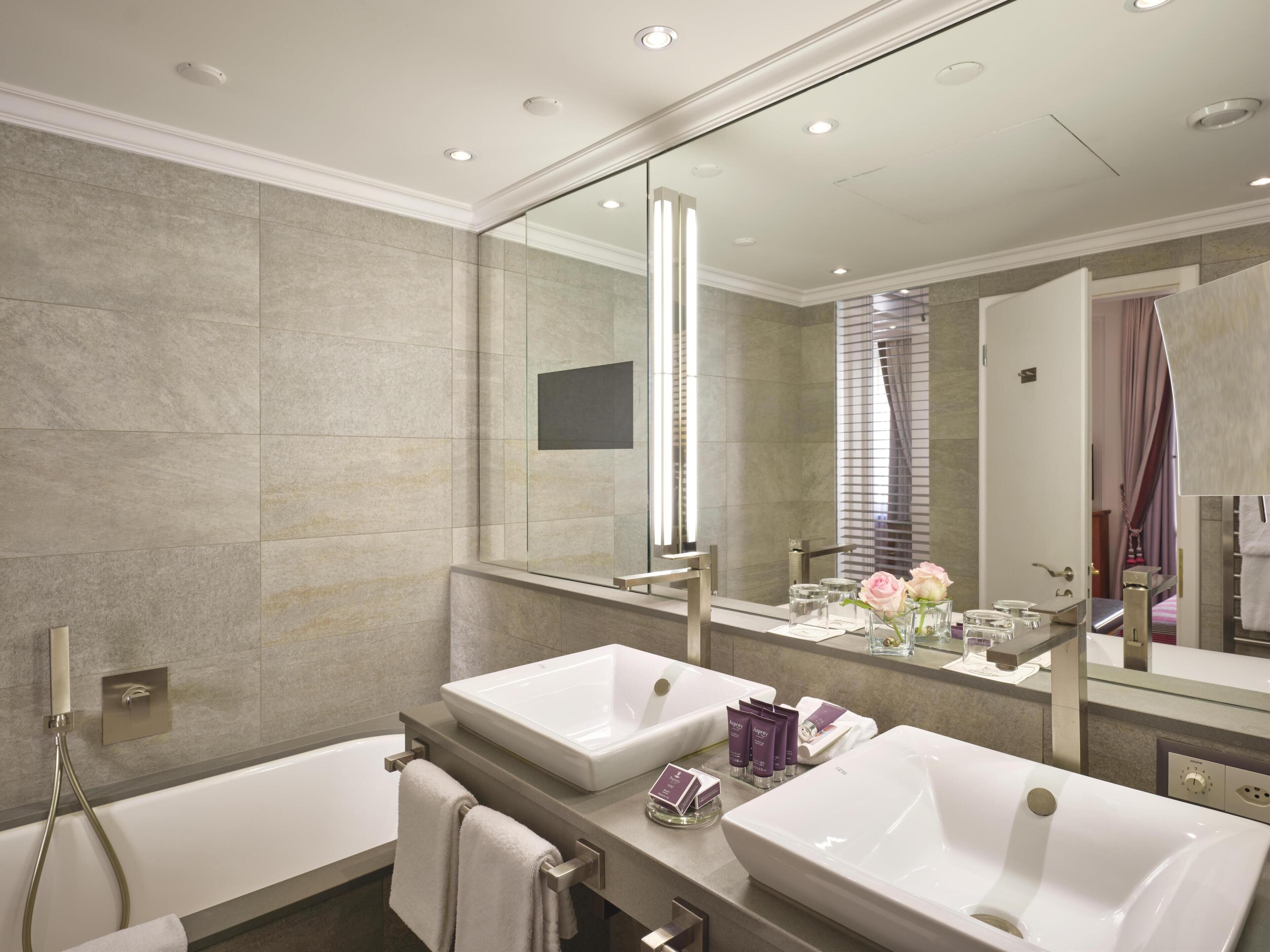 A modern bathroom with two sinks, a large mirror, and a shower.