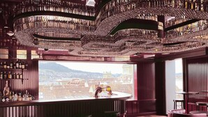 A bar with a panoramic city view, a round table, and leather seating.