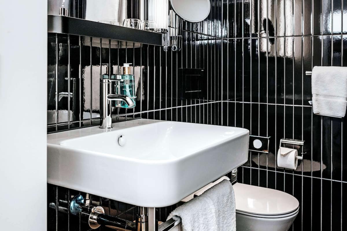 A modern bathroom with a white sink, a mirror, a toilet, and a towel rack.
