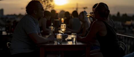 Vista del atardecer con gente cenando en una mesa al aire libre.