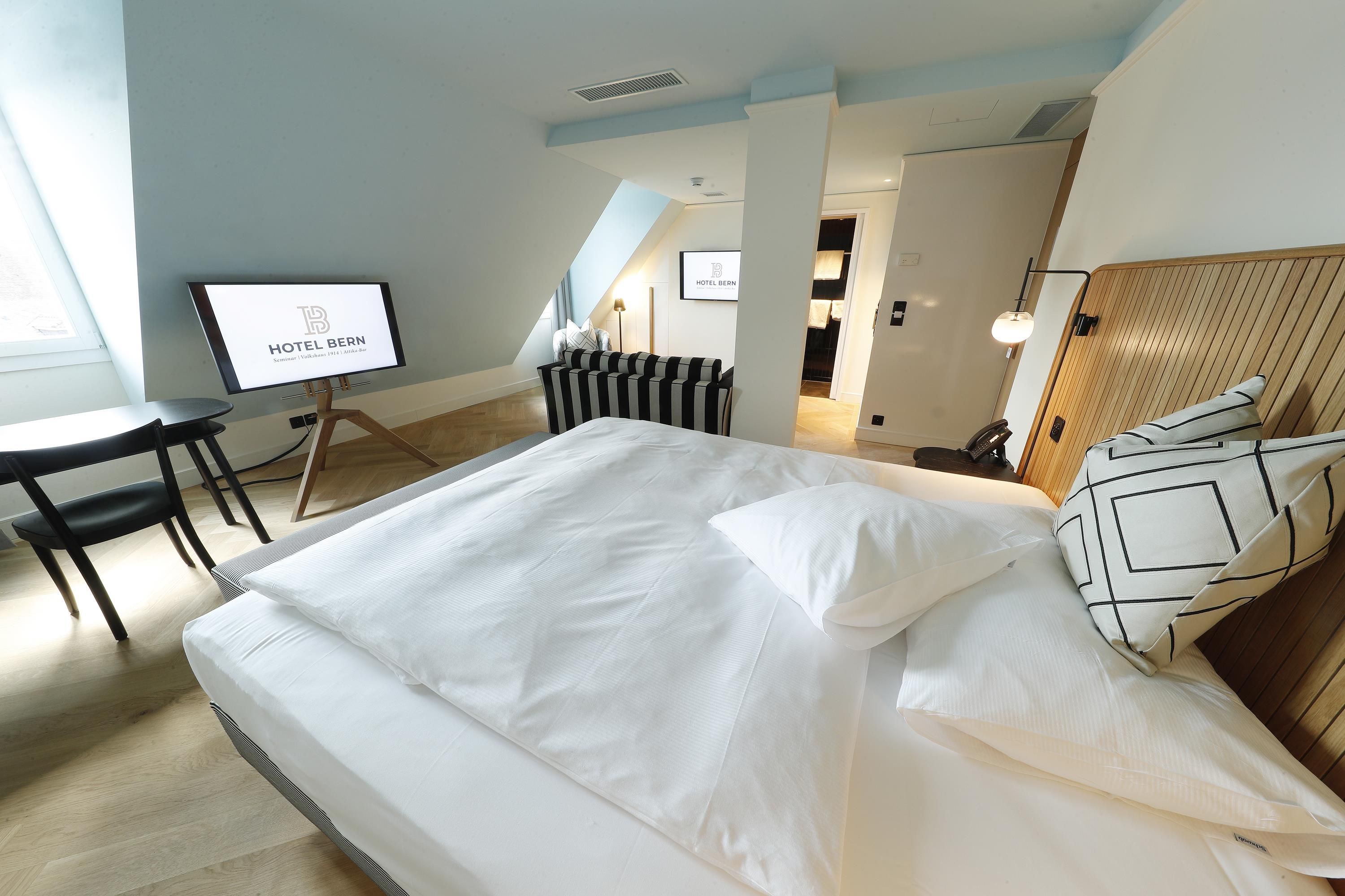 A hotel room with a bed, a desk, and a chair.