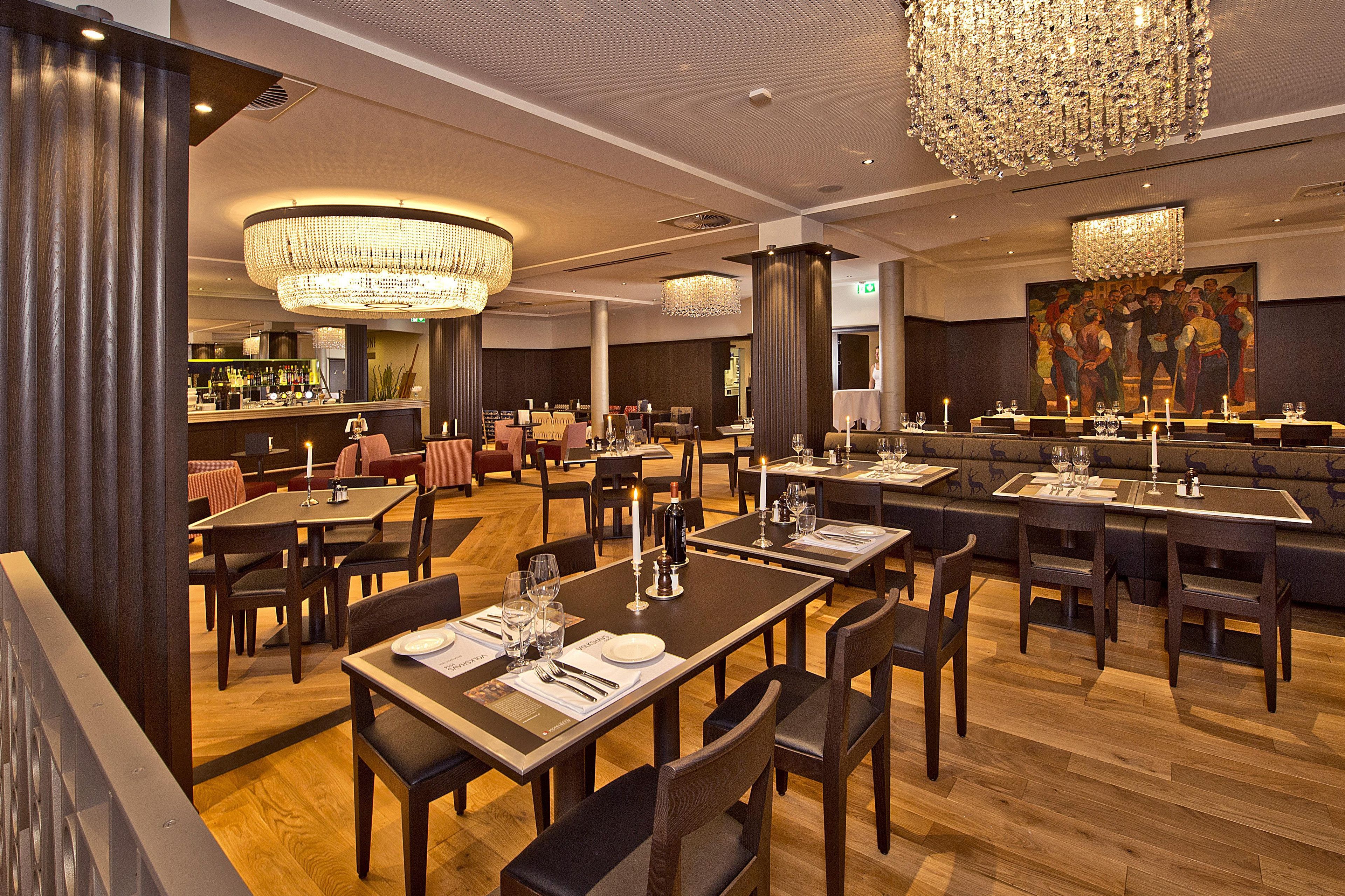 Interior de restaurante con varias mesas, sillas y una zona de bar.